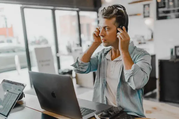 A man wearing headphones managing audio content on his digital signs.