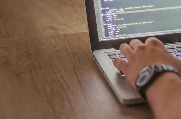 A man working on a laptop on a wood desk using inexpensive digital signage.
