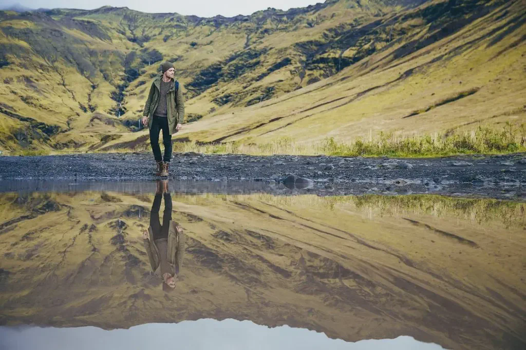 Image from NegativeSpace of a man in the mountains and his reflection on water.