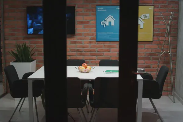 Digital signs in a modern office meeting room against a brick background.