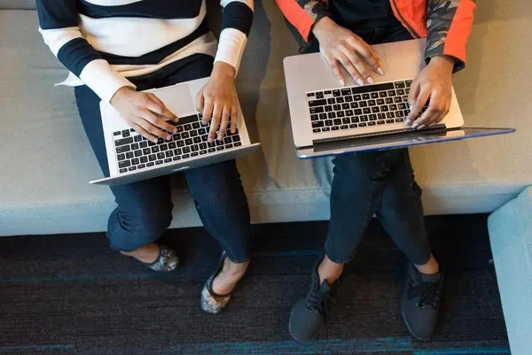 Two developers sitting with laptops switching the code base to Django.