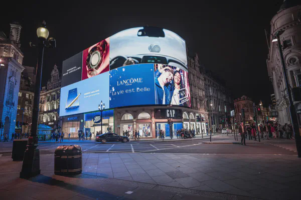 A large digital sign that wraps around the side of a building in a busy public square.